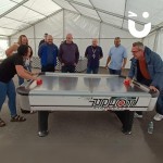 Air Hockey Table Hire at a corporate daytime event in a marquee with 2 colleagues playing and 6 colleagues watching