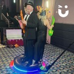 guests are wearing their props and stood on the podium of the 360 photo booth ready to capture the moment at an indoor event.