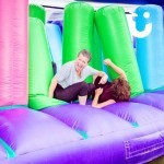 Assault Course Bish Bash Inflatable Hire at a fun day with 2 women rolling and laughing