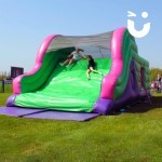 Assault Course Main Section Inflatable with 2 teenage girls holding hands sliding down end of course