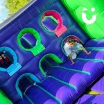 Assault Course Main Section Inflatable with a young girl crawling through a hole in the course as a fun day