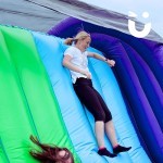 Assault Course Cargo Net Hire 8 with a woman sliding down back of inflatable at a corporate event