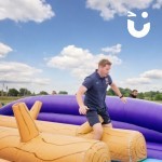 Assault Course Balance Run Outide on grass at corporate fun daywith a man running through it