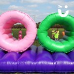 Assault Course Inflatable Tunnels 3 Hire at a team building school event with children waiting to start seen through the tunnels in team bibs