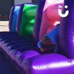 Assault Course Mangles Hire at corporate event with man in shirt climbing through inflatable