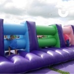 Assault Course Mangles Hire at a team build event with 3 people climbing through inflatable