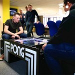Onlookers watch as employees on their lunch break take part in the Atari Pong Table Hire