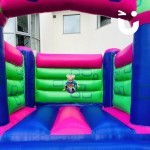 Adult Castle 5 at a community event with a toddler bouncing in the middle of the castle