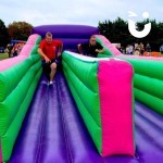 Bungee Run Hire set up at a corporate fun day with 2 male colleagues competing on the bungee run