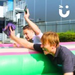 Bungee Run Hire set up at some corporate offices with 2 male colleagues enthusiastically competing on the inflatable