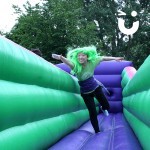 Teenager with green hair stretching to reach the end of the Bungee Run Hire