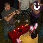 A group of spectators watch a man attempt the Hand Buzz wire Hire