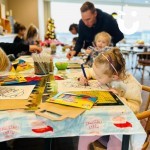 Christmas Craft Workshop Hire with children sat crafting and a dad helping his daughter