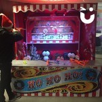 Christmas Funfair Target Stall Hire set up at an office Christmas Party with a man in a santa hat having a go