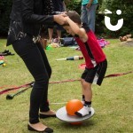 Circus Skills Workshop Hire with a mum helping her young son balance on a jumping pogo ball at a corporate fun day