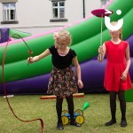 Two Girls are spinning plates and playing with a red ribbon