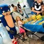 Craft Workshop at a corporate fun day with a Fun Expert dressed as Sonic the hedgehog posing with a young girl and her mum