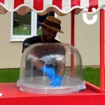 Candy Floss Cart Hire 4 at a corporate event set up outside with a fun expert smiling and making a fresh batch