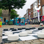 Giant Draughts set up on cobbles in a town centre