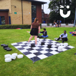 Students playing Giant Draughts on some grass on campus