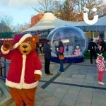 Christmas Giant Snow Globe Hire at a corporate family fun day with Santa Bear waving at the camera