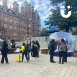 Christmas Giant Snow Globe Hire set up outside at a student event with people enjoying using it and people watching on