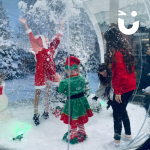 Children dressed in Christmas outfits playing inside the Giant Snow Globe