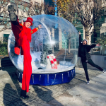 Stilt walker and Fun Expert Jenny posing beside the Giant Snow Globe