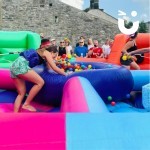 Hungry Hippos Inflatable Hire at outdoor corporate fun day being enjoyed by competitive colleagues and watched by a crowd