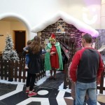Inflatable Santa's Christmas Grotto inside at a shopping centre with a mum holding her son and speaking to an elf