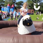 Young blonde girl on the Rodeo Sheep Hire during a family fun day