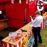 Cork Shoot Hire Image at a family fun day with a smartly dressed young boy taking aim to win a prize