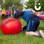 man with space hopper going under the scramble net