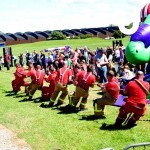 A fire crew show their strength as they take part in a Tug of War challenge at a family fun day event, where guests watch on and cheer for them.