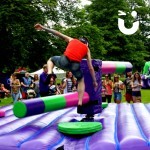 At a community fun day event, guests watch on as users of the wipeout challenge try to avoid the sweeper arms taking them out of the game.