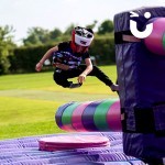 A child at a family fun day event taking on the challenge of the Wipeout Inflatable Challenge Hire, jumping over the sweeper arm as it spins round