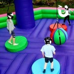 Kids enjoying the wrecking ball inflatable on hire at communit family fun day event outdoors.