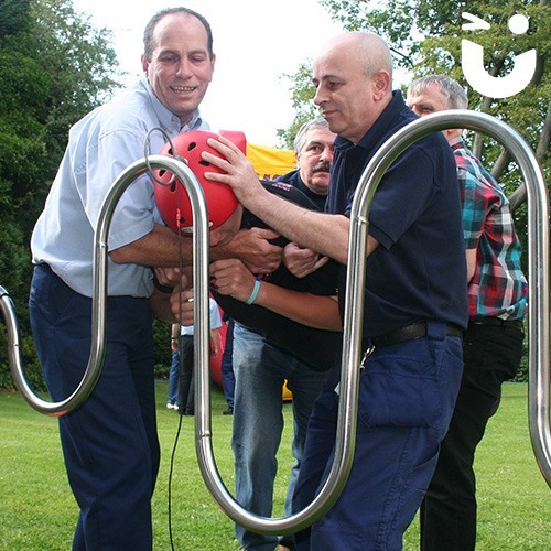 A member of a team becomes the wand for the Human Buzz Wire challenge; with the hoop on his head, the rest of the team support him and navigate him around the wand
