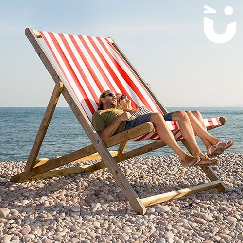 Couple on the beach relaxing on our Giant Deckchair Hire