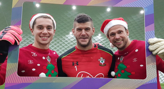 Southampton FC players wearing Christmas jumpers and posing behind a prop photo frame