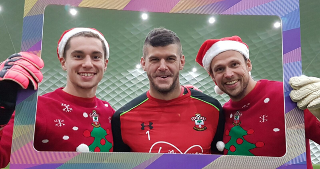 Southampton FC players wearing Christmas jumpers and posing behind a prop photo frame